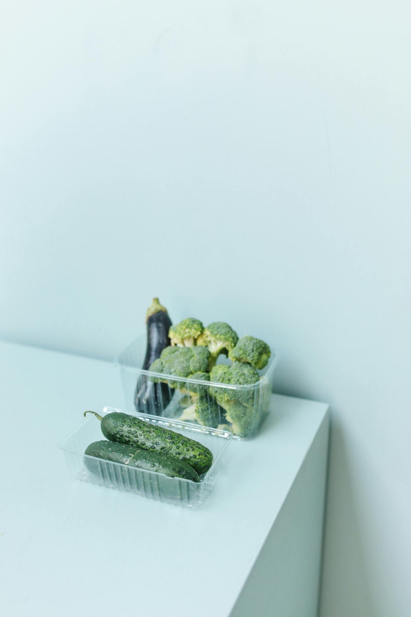 Trendy display of organic cucumbers and broccoli on a clean, white surface. Perfect for health-conscious living.